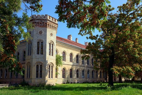 A historic Gothic-style castle surrounded by autumn trees under a clear blue sky, Officers' Palace,