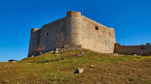 Ancient stone castle on a hill with green grass and clear blue sky, Chlemoutsi, High Medieval