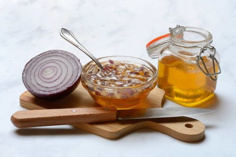 Honey in a jar and chopped onion as ingredients for cough syrup
