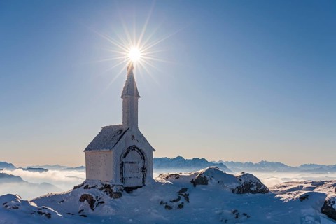 Small chapel with sun star on snowy mountain peak, backlight, winter, chapel on Hochgern, Chiemgau