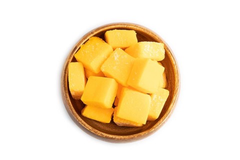 Dried and candied mango cubes in wooden bowls isolated on white background. Top view, flat lay,