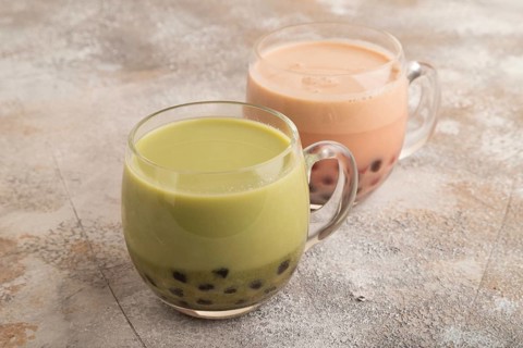 Bubble tea with pistachio and caramel in glass on brown concrete background. Healthy drink concept.
