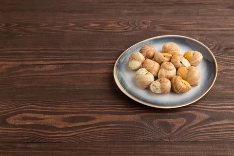 Grape (Burgundy) snails with butter and cheese on brown wooden background. Side view, copy space