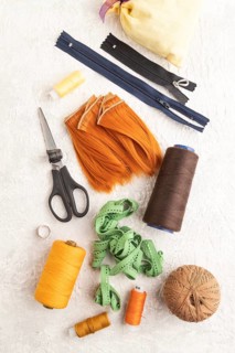 Sewing accessories: scissors, thread, thimbles, braid on gray concrete background. Top view, flat