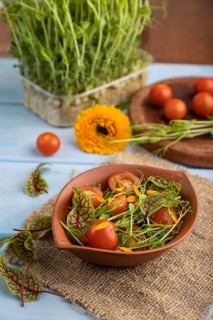 Vegetarian vegetables salad of tomatoes, marigold petals, microgreen sprouts on blue wooden