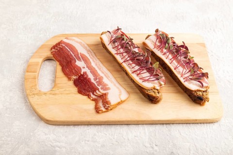 Bread sandwiches with jerky salted meat and lard with beet microgreen on gray concrete background.