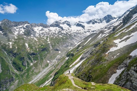 Mountaineer on hiking trail in picturesque mountain landscape, in the background mountain peak