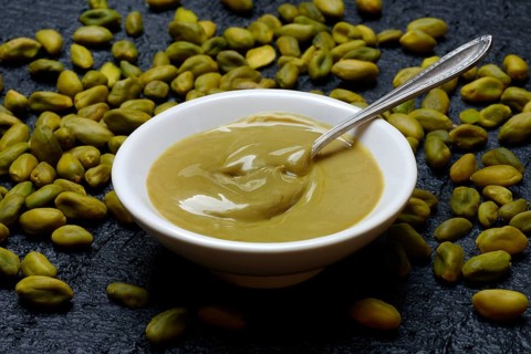 Pistachio cream in small bowls with spoon, pistachios