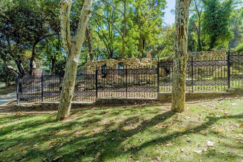 Ruins of ancient roman era behind black iron fence in public park in Istanbul, Tuerkiye