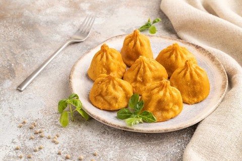 Fried manti dumplings with pepper, basil on gray concrete background and linen textile. Side view,