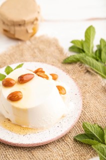 Ricotta cheese with honey and almonds on white wooden background and linen textile. side view,