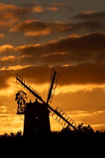 Windmill silhouetted at sunset with a red sky and clouds behind, Cley-next-to-the-sea, Norfolk,