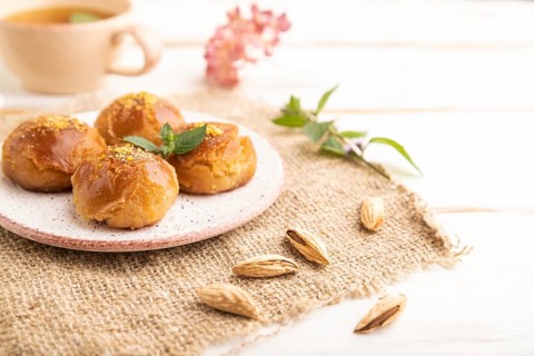 Homemade traditional turkish dessert sekerpare with almonds and honey, cup of green tea on white