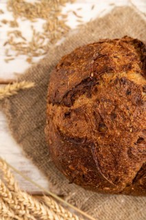 Fresh homemade golden grain bread with ears of wheat and rye on white wooden background and linen