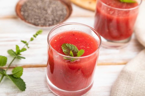 Watermelon juice with chia seeds and mint in glass on a white wooden background with linen textile.
