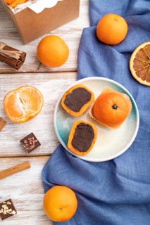 Truffle chocolate tangerine candies on a white wooden background and blue linen textile. top view,