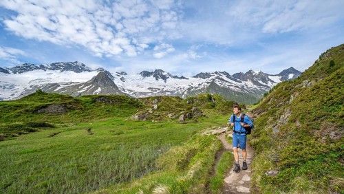 Mountaineer on hiking trail in picturesque mountain landscape, mountain peaks with snow and glacier