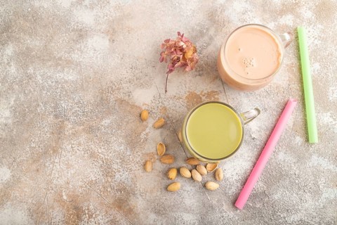 Bubble tea with pistachio and caramel in glass on brown concrete background. Healthy drink concept.