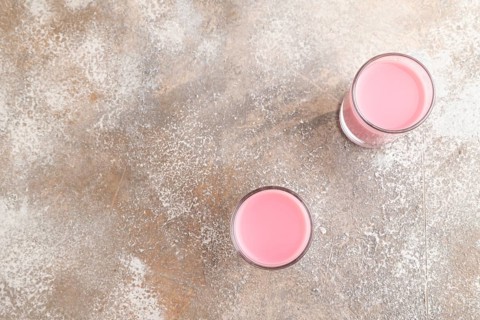 Sweet strawberry liqueur in glass on a gray concrete background. top view, copy space, flat lay