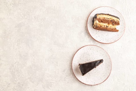 Chocolate biscuit cake with caramel cream and walnuts, on gray concrete background. top view, flat