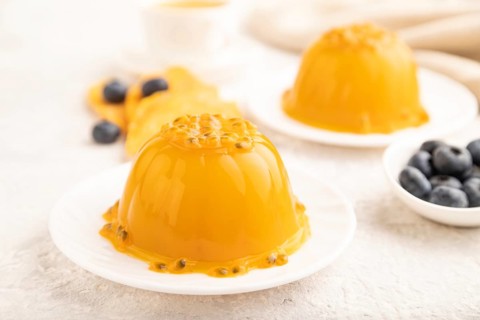Mango and passion fruit jelly with blueberry on gray concrete background and linen textile. side