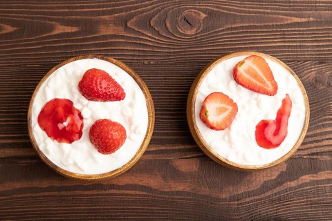 Grained cottage cheese with strawberry jam on brown wooden background. top view, flat lay, copy