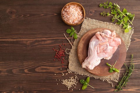 Raw turkey wing with herbs and spices on a wooden cutting board on a brown wooden background and
