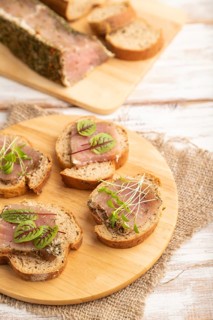 Bread sandwiches with jerky salted meat, sorrel and cilantro microgreen on white wooden background