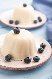 White milk jelly with blueberry on blue wooden background and blue linen textile. side view, close