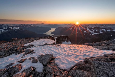 View of mountains and fjord Faleidfjorden, sun star at sunset, summit of Skala, Loen, Norway,