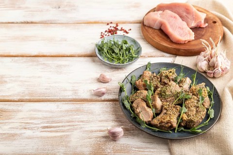 Stewed turkey fillet with garlic and sprouts of green peas on white wooden background and linen