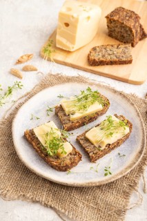 Grain bread sandwiches with cheese and watercress microgreen on gray concrete background and linen