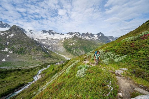 Mountaineer on hiking trail in picturesque mountain landscape, mountain peak with snow and glacier