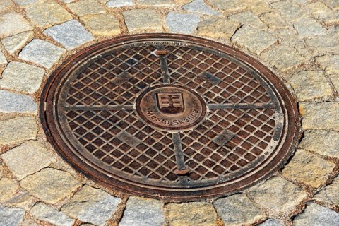A metal manhole cover on a paved road surface, symmetrical and stable, manhole cover, Skalica,