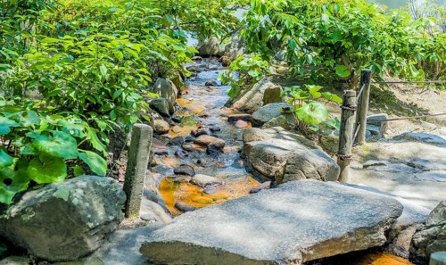 Small creek flowing under concrete footbridge in Japanese garden park in Hiroshima, Japan, Asia