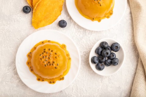 Mango and passion fruit jelly with blueberry on gray concrete background and linen textile. top