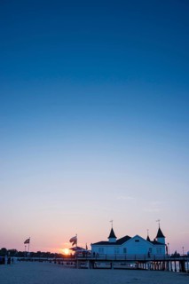 People strolling on a pier with buildings in the sunset, clear, blue, cloudless sky, pier Ahlbeck