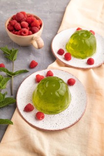 Mint and raspberry green jelly on gray concrete background and orange linen textile. side view,