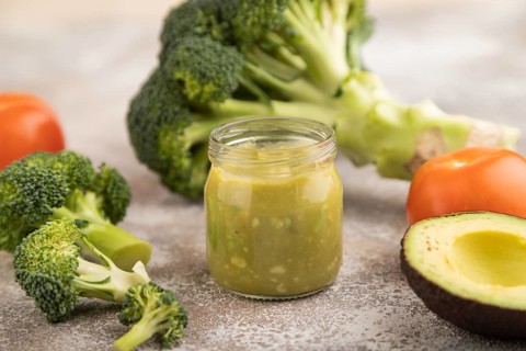 Baby puree with vegetable mix, broccoli, tomatoes, cucumber, avocado infant formula in glass jar on