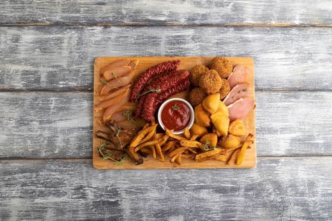 Set of snacks: sausages, fried potatoes, meat balls, dumplings, basturma on a cutting board on a