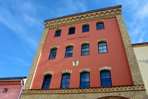 View of a historic red brick building with the nameplate 'Torres Daniela' under a blue sky, Torre