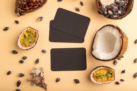 Brown paper business card with coconut, passion fruit, seashells, on orange pastel background. Top