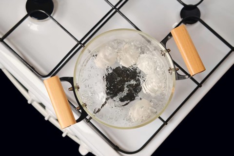 Top view of transparent glass saucepan with boiling eggs on a gas stove