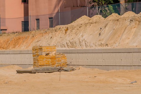 Concrete forms and iron scaffold pipes stacked neatly in front of concrete wall at construction