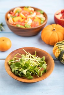 Sunflower microgreen sprouts and vegetarian fruit salad of pumpkin, tangerine, pomegranate,