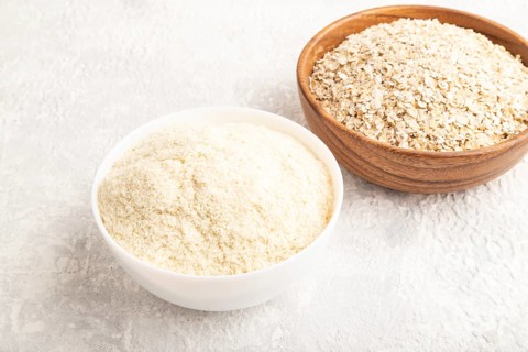 Powdered milk and oatmeal, baby food mix, infant formula on gray concrete background. Side view,