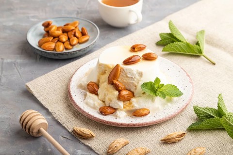 Ricotta cheese with honey and almonds on gray concrete background and linen textile. side view,