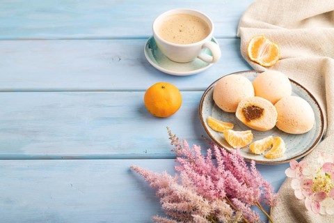 Japanese rice sweet buns mochi filled with tangerine jam and cup of coffee on a blue wooden