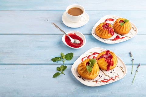 Semolina cheesecake with strawberry jam, lavender, cup of coffee on blue wooden background. side