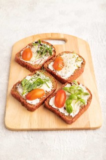 Red beet bread sandwiches with cream cheese, tomatoes and microgreen on gray concrete background.